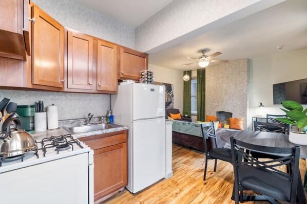 Kitchen area with gas stove, refrigerator, and dining space with a round table and chairs.