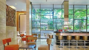 A modern bar area with a glass partition, seating with cushioned chairs, and a view of greenery through large windows. - Double-Bedroom With Terrace In Seminyak (Bali)