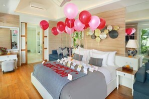 A modern bedroom with a large bed, a bedside table, a nightstand, and a wall decorated with balloons.