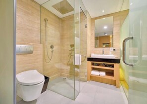 A modern bathroom with a glass shower enclosure, a toilet, a sink with a mirror, and a vanity with towels. - Superior Double-bedroom With Terrace (Bali)