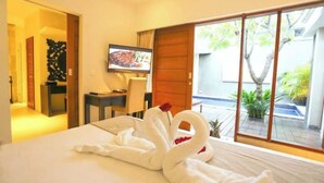 A hotel room with a bed, a TV, a desk, and a view of the outside.