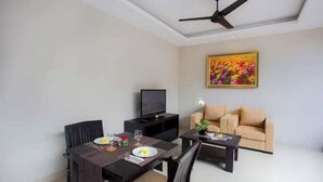 A modern living room with a dining table, a sofa, a TV, and a ceiling fan.