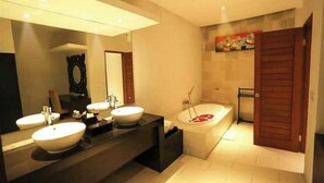 A modern bathroom with two sinks, a large mirror, a bathtub with rose petals, and a wooden door.