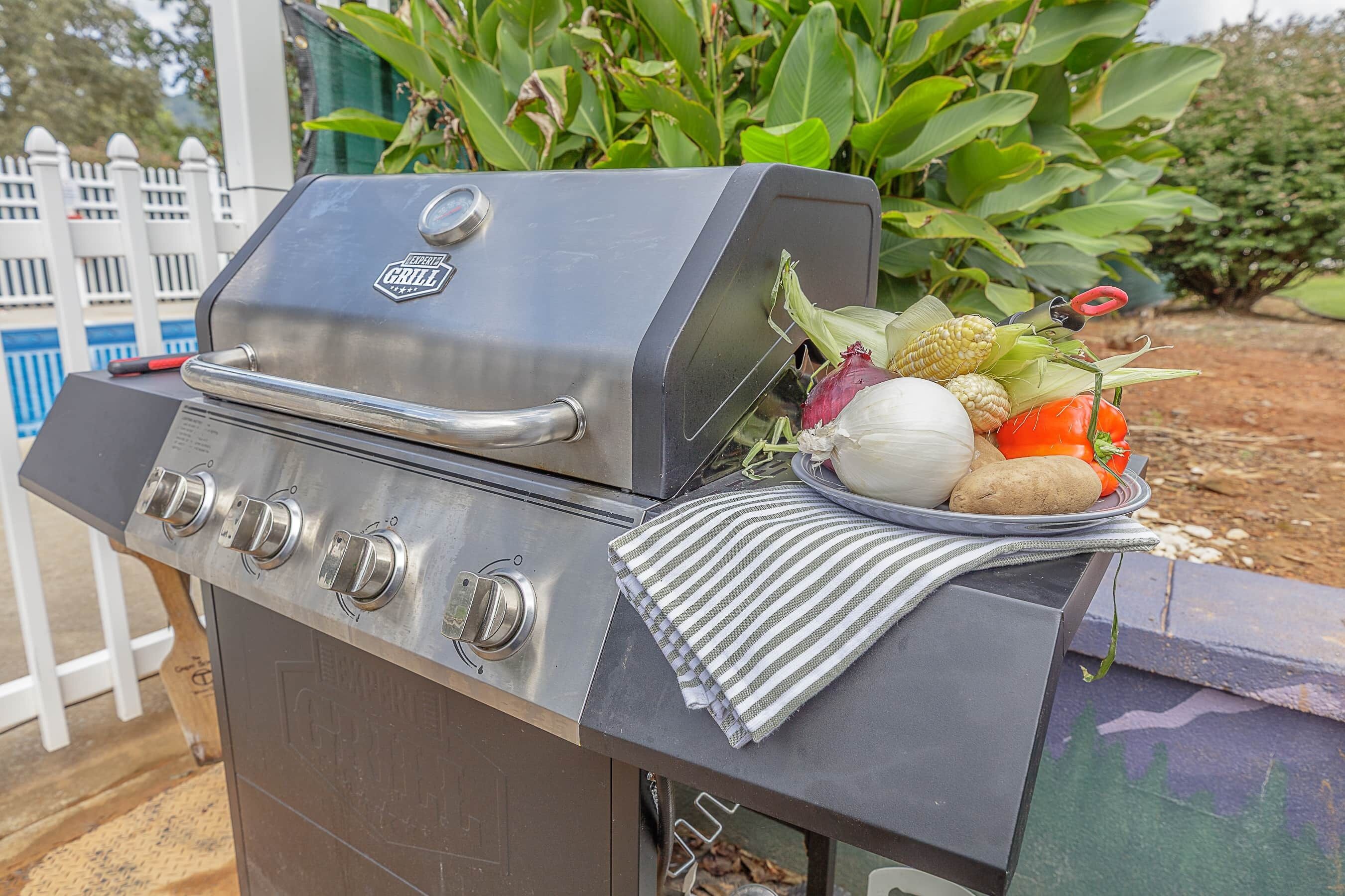Una barbacoa amb acabat d'acer inoxidable, un panell de control amb quatre botons i una tapa per a la graella.