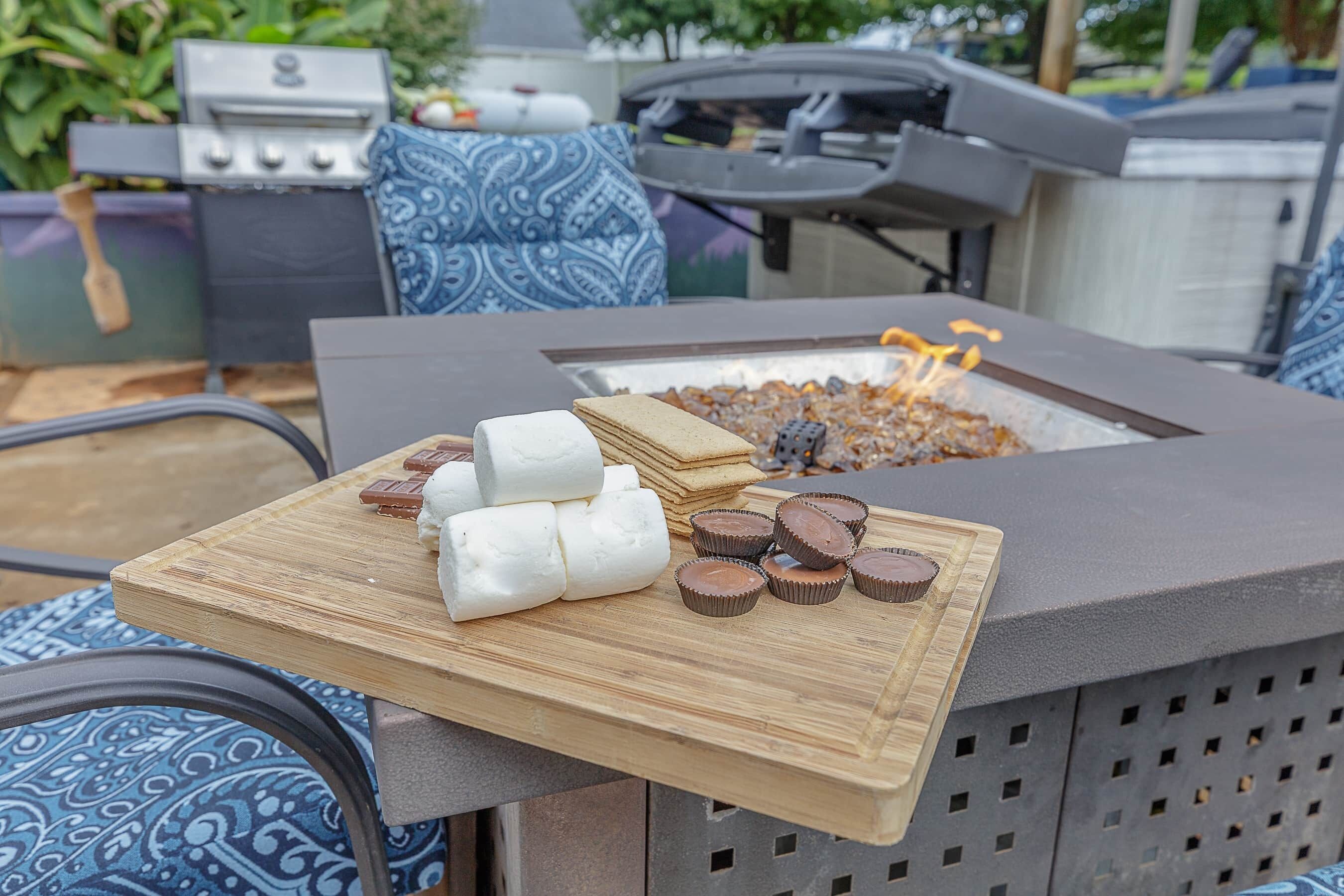 Een buitenbarbecue en vuurkuil met een houten tafel ervoor.
