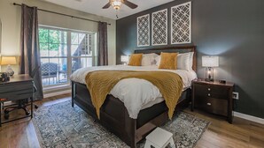 Un dormitorio con una cama grande, un ventilador de techo, un escritorio con lámpara y vistas al exterior.