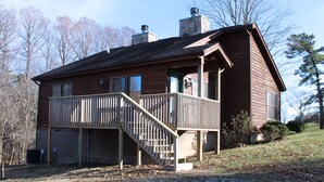 Une maison en bois à deux étages, dotée d’un balcon et d’une cheminée.