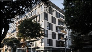 Een modern, meerlaags gebouw met balkons, grote ramen en een voetgangerspad.