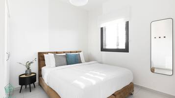 A modern bedroom with a bed, bedside table, and a mirror.