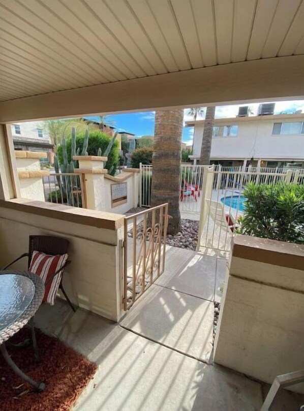 Relax on the covered patio with a view of the pool and surrounding buildings.