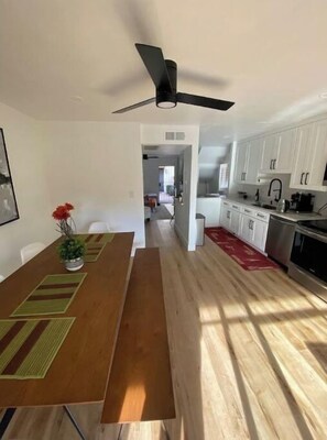 Enjoy meals in this dining area with a wooden table and chairs, a ceiling fan, and a vase with flowers.