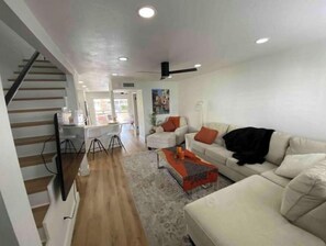 Relax in this inviting living space with a staircase leading to an upper level, a comfortable sofa, and a stylish coffee table.