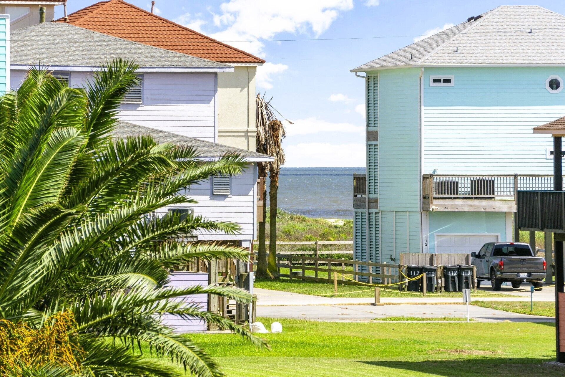 Zona residencial costera con casas, una camioneta SUV estacionada y una vista despejada del océano.
