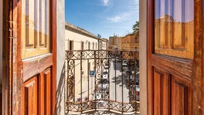 Vista a través de una reja de hierro forjado hacia una calle con coches aparcados y edificios.