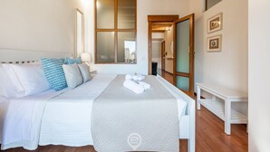 Un dormitorio con una cama grande, techo de madera, una ventana y una puerta que da a otra habitación.