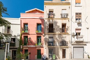 A row of multi-story buildings with balconies, some with plants.
