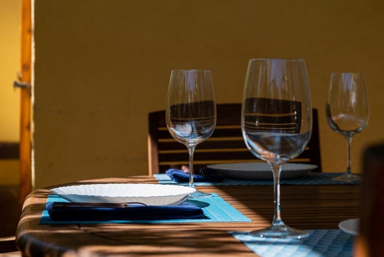 Een eettafel met twee wijnglazen, een wit bord en een blauwe servet.
