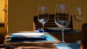 Una mesa de comedor con dos copas de vino, un plato blanco y un guardanapo azul.