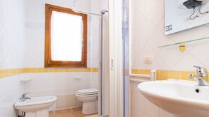 Un baño con ducha, inodoro, bidé y lavamanos.