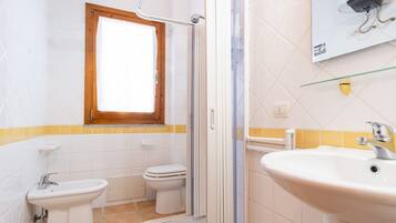 Een badkamer met douche, toilet, bidet en wastafel.