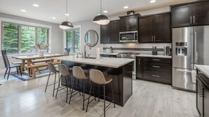 A modern kitchen with dark cabinets, stainless steel appliances, and a central island with bar stools. - Family Friendly w/ Suncadia Pool Access (Cle Elum)