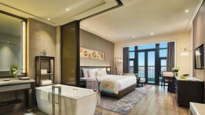 Une chambre d’hôtel moderne dotée d’un grand lit, d’une salle de bain séparée, d’un bureau et d’un balcon avec vue.