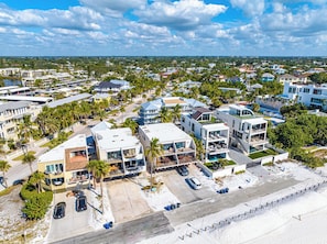 Vista aérea de uma área residencial costeira com casas modernas, piscina e praia.