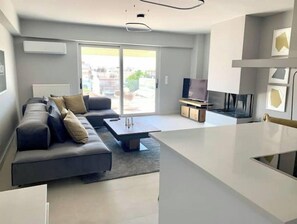 Relax in this stylish living room with a comfortable sofa, flat-screen TV, and sliding glass door to an outdoor area.