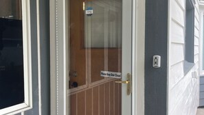 Eine Haustür mit einem Schild 'Bitte Tür geschlossen halten', einem Klingelknopf und einem Fenster mit einem Schild mit der Aufschrift 'Klingeln'.