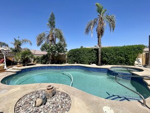 Ein Swimmingpool mit Kiesbord, Palmen und blauem Himmel.