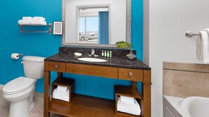 A bathroom with a blue accent wall, a white toilet, a sink with a mirror, and a shower area.