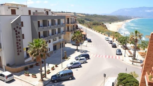 A coastal hotel with a view of the beach, multiple parking spaces, and a street with cars. - Residence Eloisa  (Balestrate)