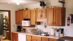 Una cocina con armarios de madera, un microondas y diversos utensilios de cocina sobre la encimera.