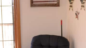 Une pièce avec une grande fenêtre, un fauteuil bleu et des drapeaux américains accrochés au mur.