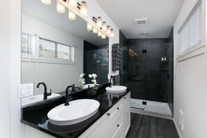 A modern bathroom with two sinks, a large mirror, and a glass shower enclosure. - Epic Columbia River views * New Modern Home in the heart of the gorge. (Carson)