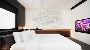 A modern hotel room with a large bed, a flat-screen TV, and a wall with a map.