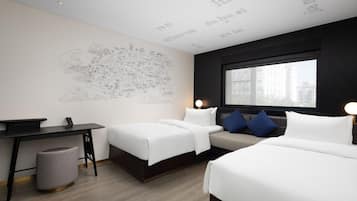 A hotel room with two beds, a desk, a chair, a trash bin, and a large window.