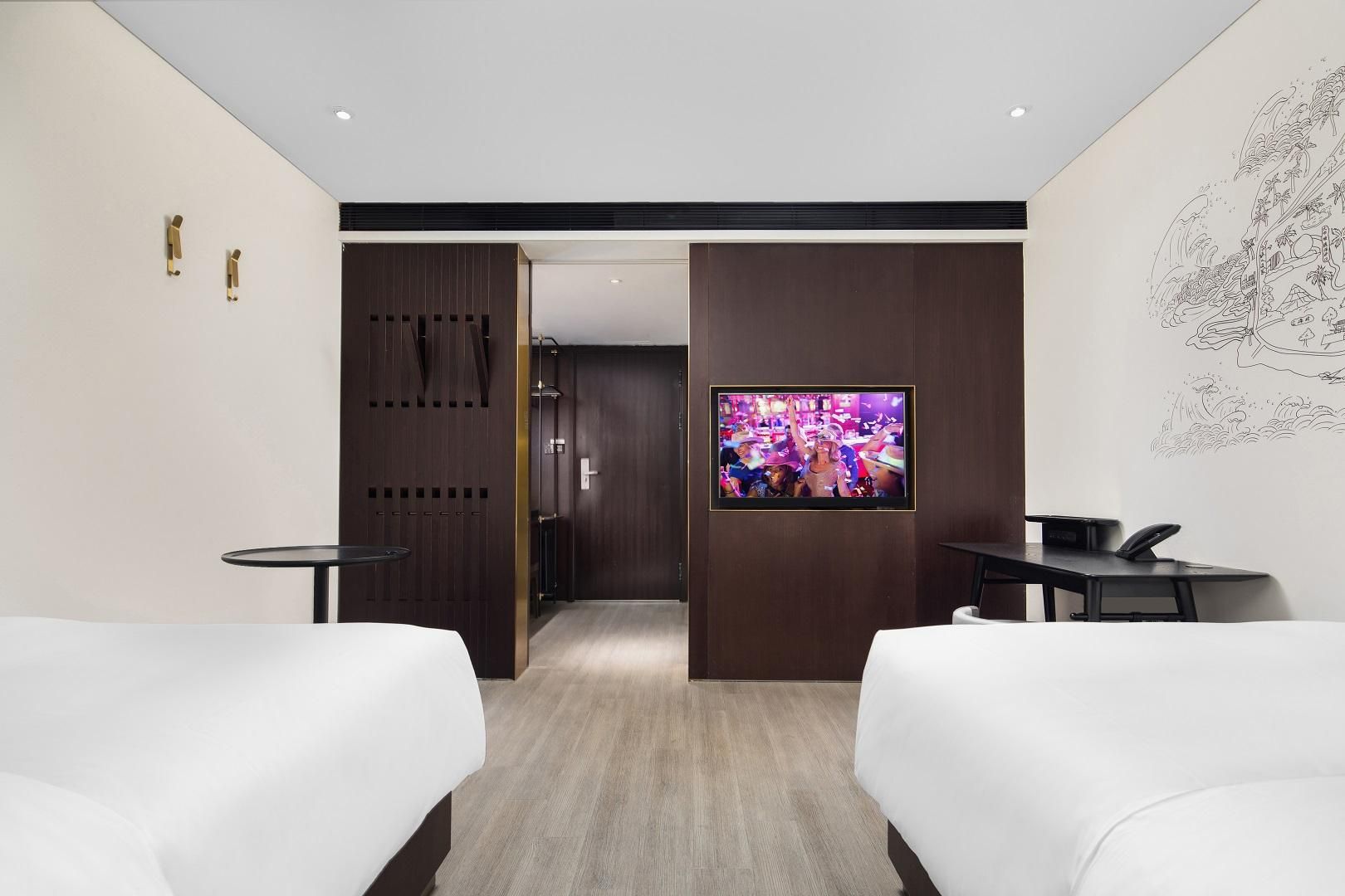 Une chambre d’hôtel avec deux lits, une télévision, un bureau et un mur recouvert de panneaux de bois.