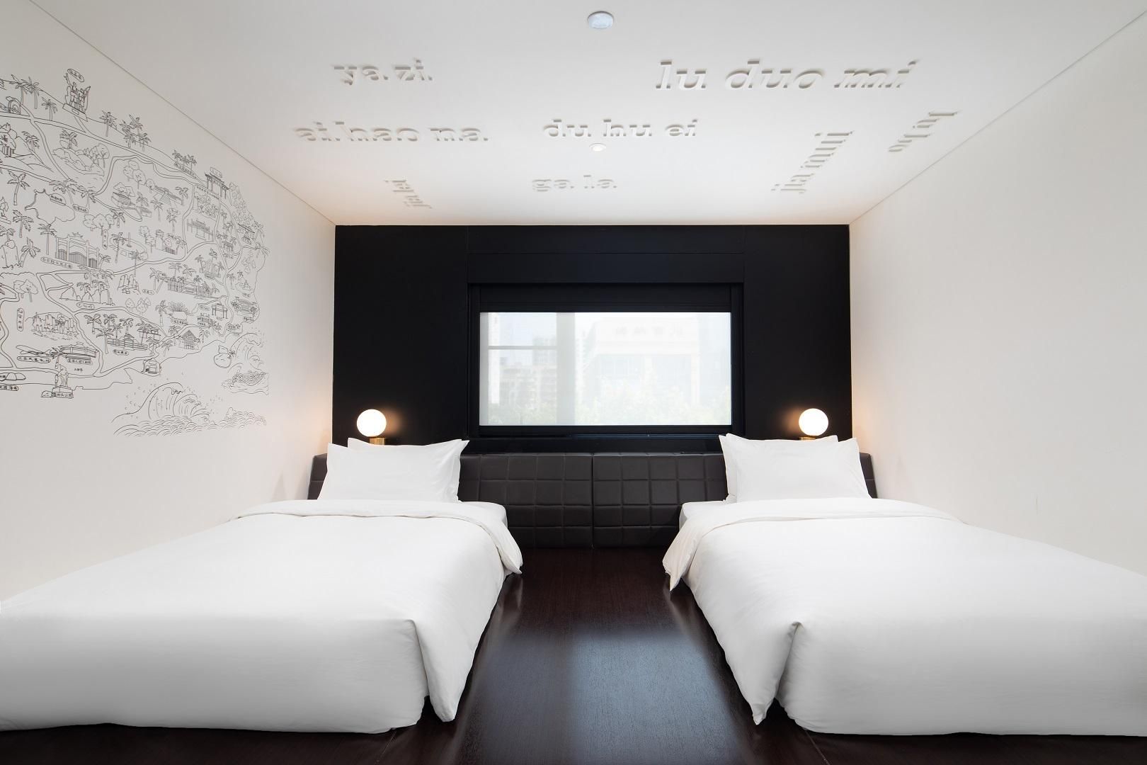 Een moderne hotelkamer met twee eenpersoonsbedden, een groot raam en een muur met een kaart.