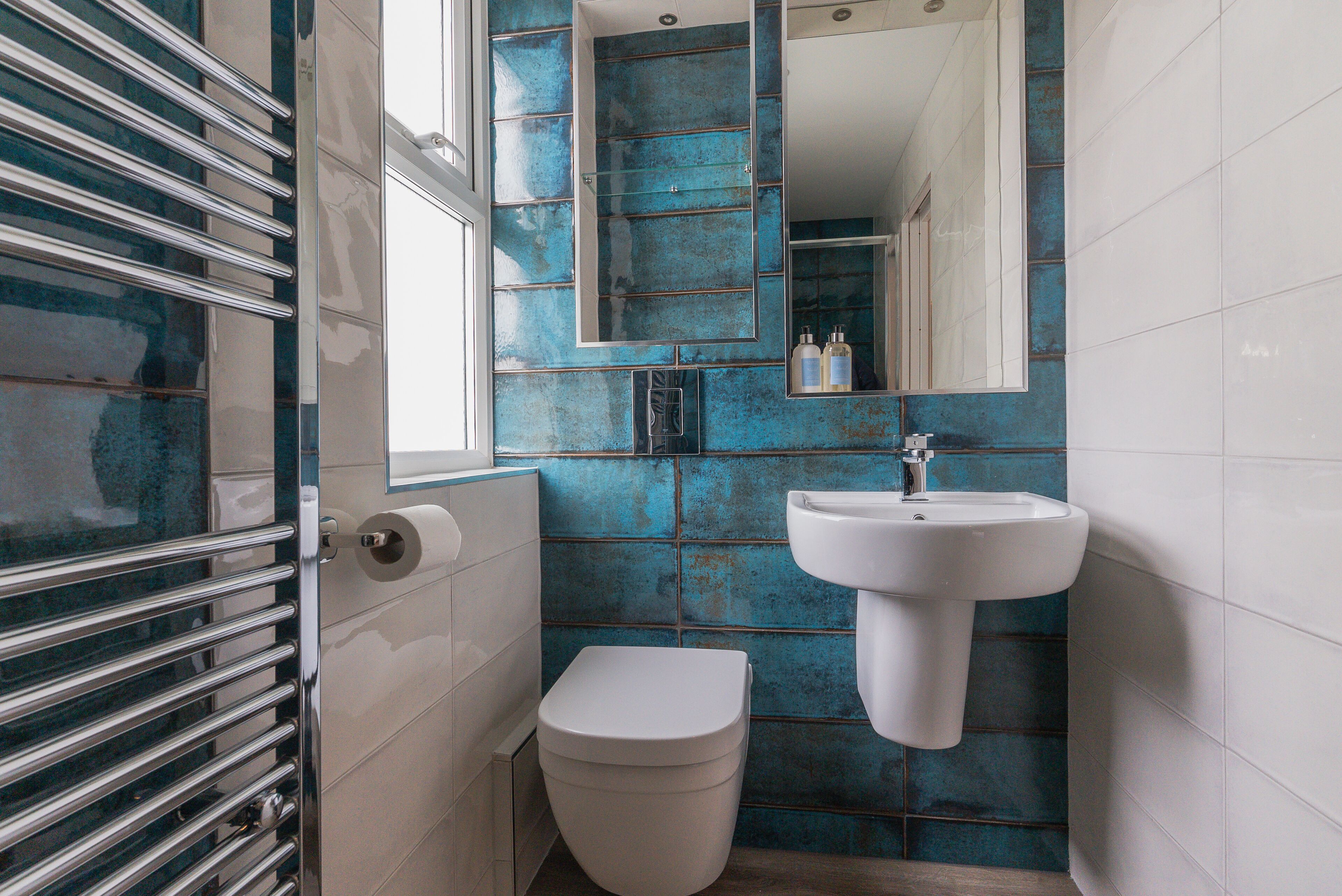 Un baño con inodoro blanco, lavamanos y espejo.