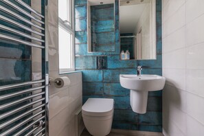 A bathroom with a white toilet, a sink, and a mirror. - Carrick Rooms (Port St Mary)