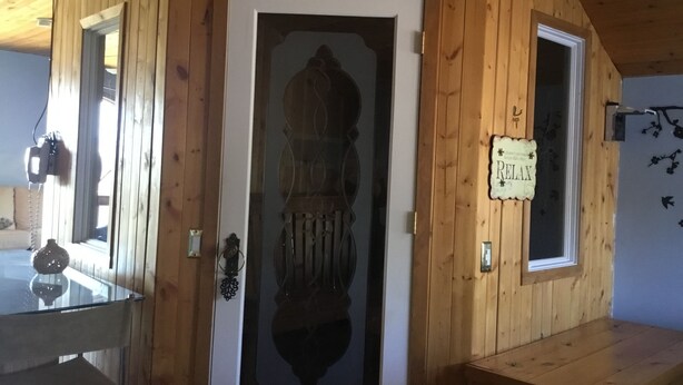 Interior de madera con un cartel de sauna, un cartel de relajación y una puerta de cristal con reflejo.