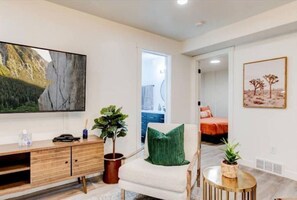 Relax in a serene space with a large flat-screen TV, comfortable armchair, and a cozy bed.