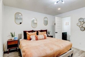 Relax in a serene bedroom with a large bed, two nightstands, and elegant mirrors.