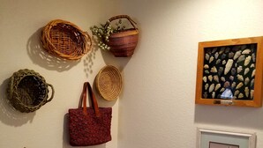 Ein Zimmer mit einer Eckenwand, verziert mit Körben, einer gewebten Tasche, einem gerahmten Bild und einem Kunstwerk.