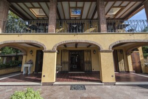 Een gebouw met twee verdiepingen, een balkon, boogvormige deuropeningen en een betegeld entreegebied.