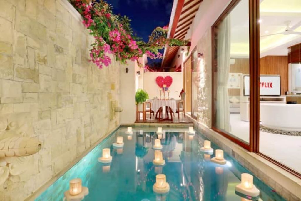 A swimming pool with candles, a heart-shaped decoration, and a Netflix sign.