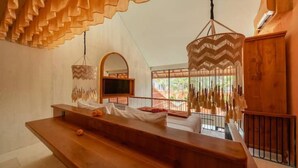 Een modern interieur met een houten bank, hangende lampen en een balkon met een hekwerk.