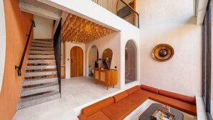 Een modern interieur met een trap, een zithoek en een houten plafond.