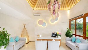 A modern interior with a reception desk, two white sofas, and a large window. - Glamour 1BR Private Villa Kuta (Bali)